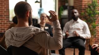 People seated in a circle talking and wearing name tags. 